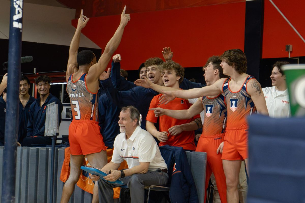 Junior all-around Amari Sewell celebrates with his team after completing his floor routine during the game against Michigan yesterday. 