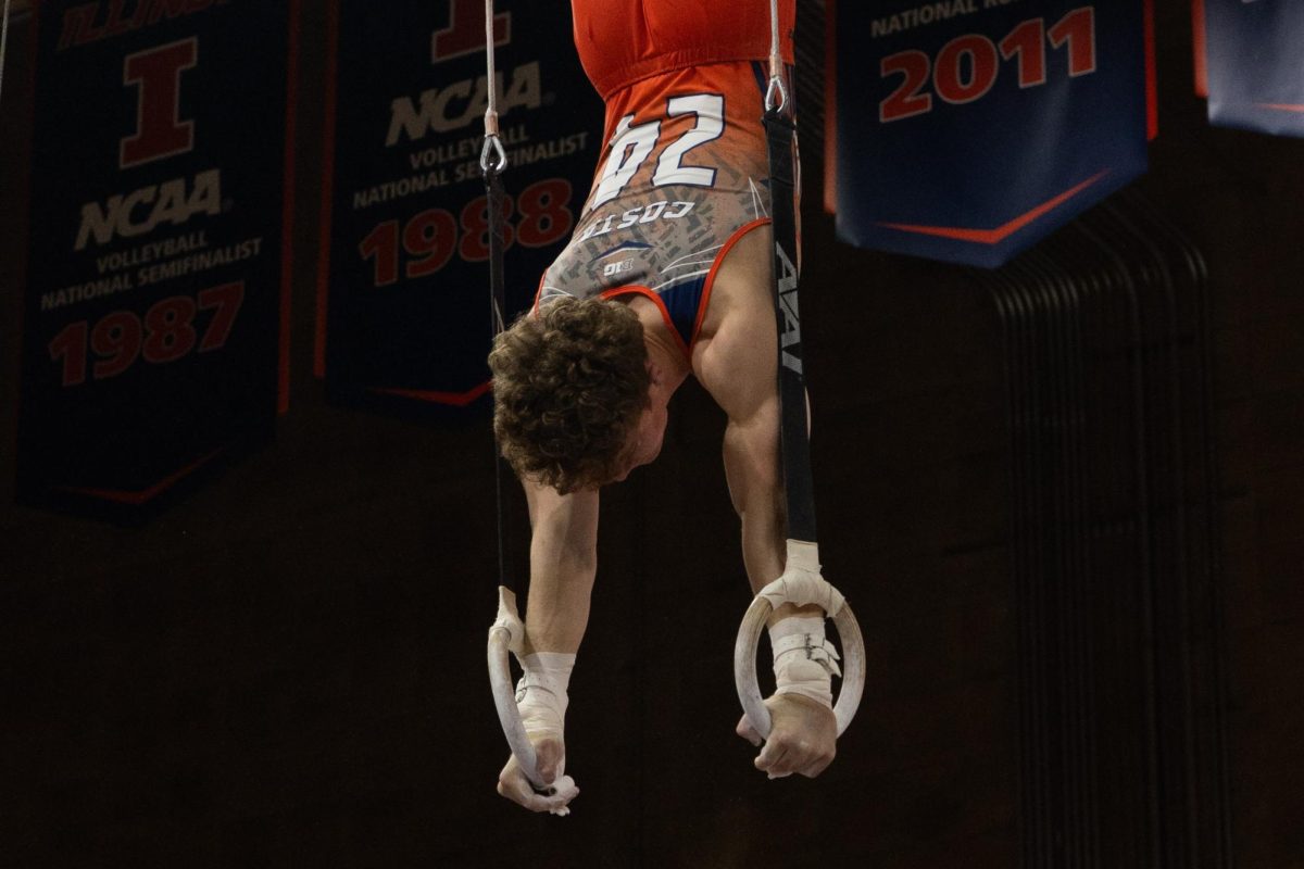 Sophomore Tate Costa holds a handstand on the rings during the meet against Michigan on Feb. 3.