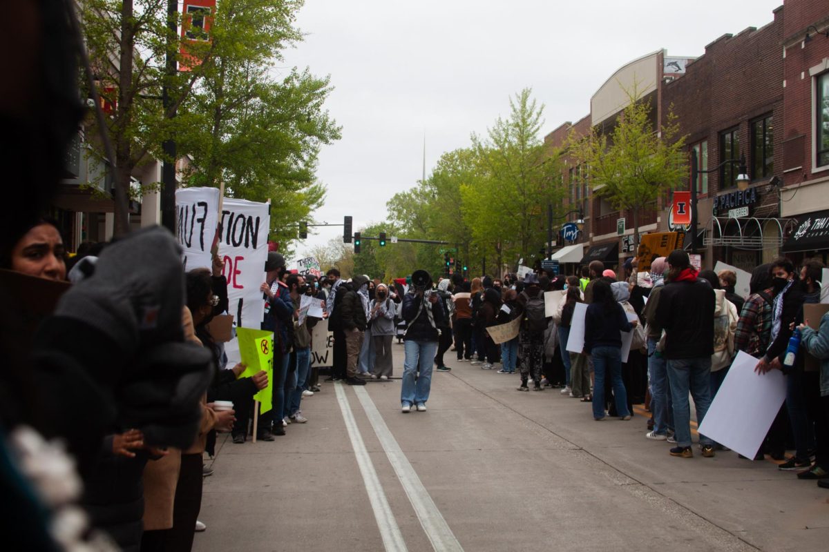 Protesters circle on Green Street, an organizer leads chants from the middle of the circle with a megaphone.