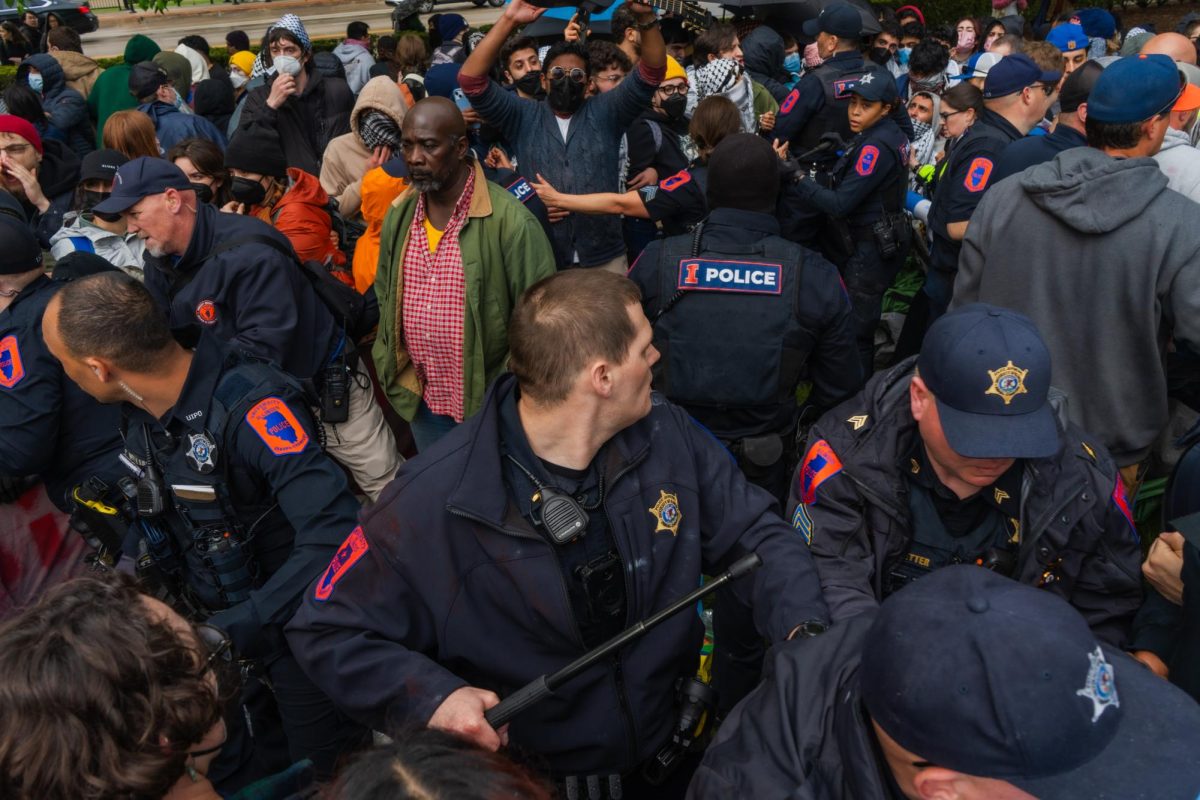 A CU police officer brandishes his nightstick while attempting to breach the circle of protesters to remove tents during the encampment protest next to the Alma Mater.