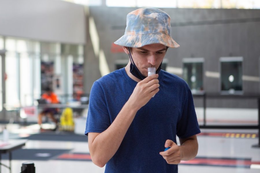 A student deposits saliva into a University COVID-19 test tube while taking a COVID-19 test at State Farm Center on Oct. 9.