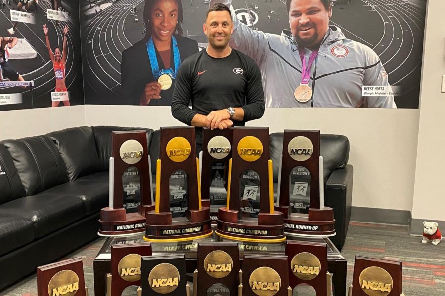 Petros Kyprianou, new Illinois track and field and cross country director, stands alongside trophies won during his time as the Georgia head coach. Kyprianou spent 13 years working with Georgia. 