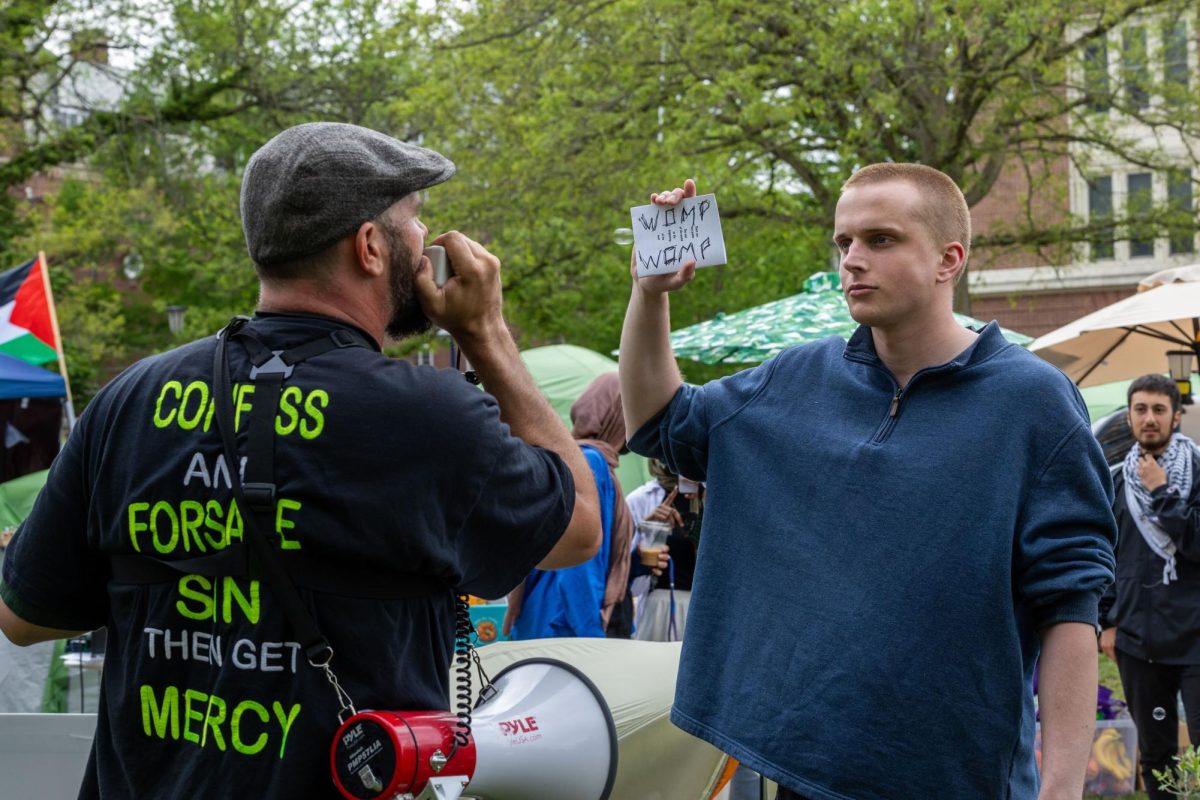 Protesters hold up signs confronting the preacher who appeared in the encampment with a megaphone on Friday.